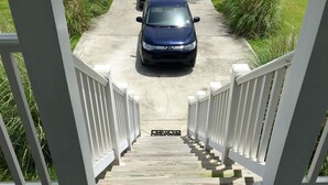 A wooden staircase leading to a driveway with a car parked on it. - Peaceful Gulf Getaway - Close to Old Town Bay St Louis (Bay St Louis)