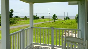 A porch with a view of a grassy field and a road. - Peaceful Gulf Getaway - Close to Old Town Bay St Louis (Bay St Louis)