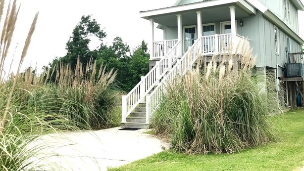 A two-story house with a front porch and a staircase leading to the entrance. - Peaceful Gulf Getaway - Close to Old Town Bay St Louis (Bay St Louis)