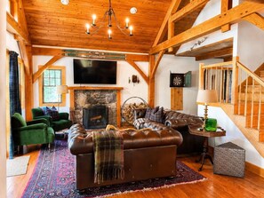 Una sala de estar acogedora con chimenea, sofá de cuero y televisor.
