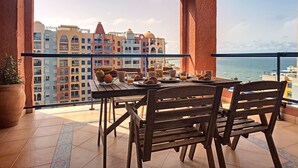 Een balkon met een ontbijtje, met uitzicht op een stadsgezicht en de zee.