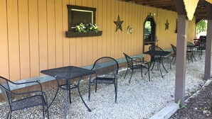 An outdoor patio with metal tables and chairs, a wooden wall with a window, and decorative stars. - Private Chalet with a View (Geneva)