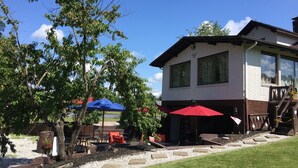 A two-story building with a brick exterior, large windows, and a covered outdoor seating area with red and blue umbrellas. - Private Chalet with a View (Geneva)