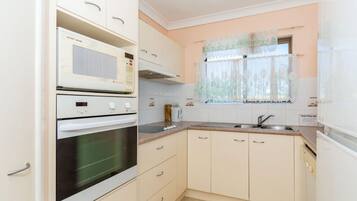 A compact kitchen with a built-in oven, microwave, and a small countertop.