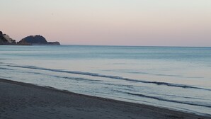 A beach with calm water and a distant rocky outcrop. - Three-room apartment in a strategic location between downtown and the sea CIN IT009002C2KQ9JCI5G (Albenga)