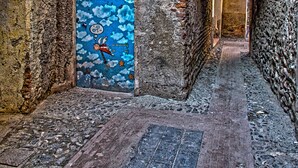 A narrow alleyway with a blue door featuring a whimsical design, flanked by stone walls and a brick pathway. - Three-room apartment in a strategic location between downtown and the sea CIN IT009002C2KQ9JCI5G (Albenga)