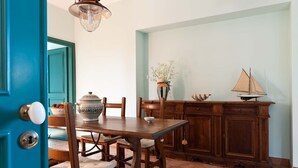 A dining area with a wooden table, chairs, a cabinet, and a decorative sailboat. - Holiday apartment with sea access on the Ionian Coast, Sicily (Torre Archirafi)