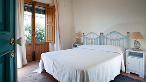 A bedroom with a bed, nightstands, and a wooden door with curtains. - Holiday apartment with sea access on the Ionian Coast, Sicily (Torre Archirafi)