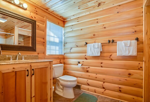 A wooden-paneled bathroom with a sink, toilet, and mirror.