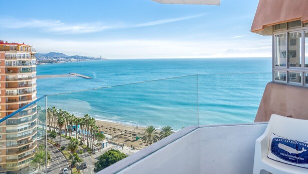 Un balcon avec vue sur l’océan, une plage et un immeuble doté de balcons.
