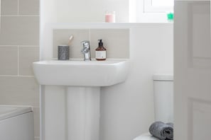A bathroom with a white sink, a toothbrush holder, and a hand soap bottle. - Canalside Scandinavian - Parking & Netflix (Coventry)