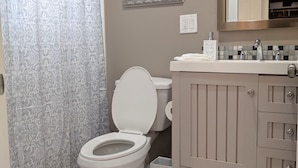 A bathroom with a toilet, a sink, a mirror, and a shower curtain.