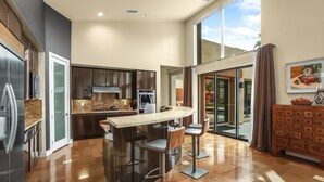 A modern kitchen with a central island, bar stools, and a large window. - Luxury Palm Springs Retreat. Pool, Spa & Stunning Mountain Views (Palm Springs)