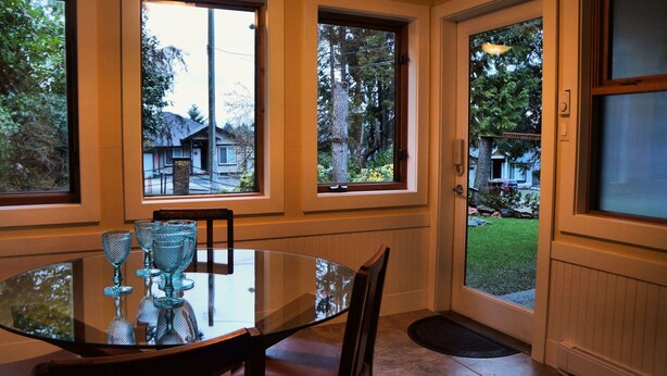 Un comedor con una mesa y sillas de vidrio, ventanas amplias y vistas al exterior.