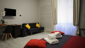 Habitación de hotel moderna con cama, escritorio, silla, televisión y ventana con cortinas.