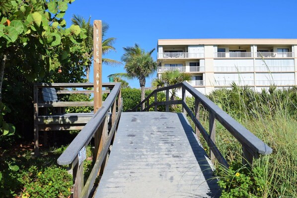 A wooden boardwalk leading to a building with balconies.