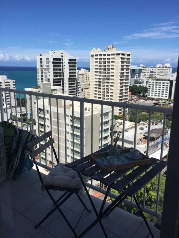 A balcony with a view of tall buildings and the ocean. - Chic Bright Beautiful Studio with Ocean View CONDADO and parking (San Juan)