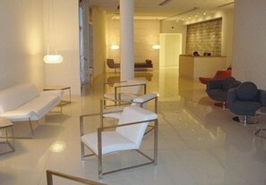 Un hall d’hôtel moderne comprenant un comptoir d’accueil, un espace détente et un bureau d’enregistrement.