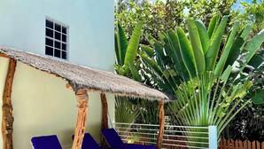 A poolside area with lounge chairs, a thatched roof structure, and tropical plants. - Villa, Pool, AC, Dock and Beach access Paddle boards (Caye Caulker)