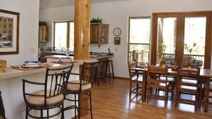 Una cucina spaziosa con mobili impiallacciati in legno, un'isola centrale con sgabelli da bar e ampie finestre che lasciano entrare luce naturale.