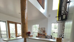 Una stanza spaziosa con un tavolo di legno, uno sgabello e una finestra vista verde.