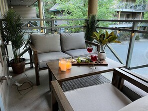 A balcony with a sofa, a table with drinks and snacks, and potted plants.