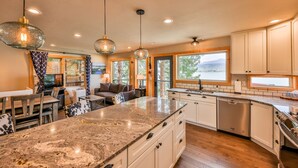 A modern kitchen with granite countertops, stainless steel appliances, and large windows offering a view of the outdoors. - Quintessential Lake House on the shore of GL,  awe-inspiring views (Grand Lake)