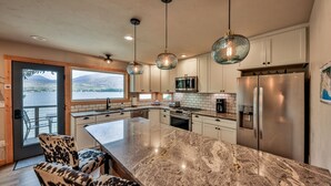 A modern kitchen with a large island, stainless steel appliances, and pendant lighting. - Quintessential Lake House on the shore of GL,  awe-inspiring views (Grand Lake)
