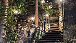 A wooden staircase with metal railings, surrounded by rocks and vegetation, leading up to a wooden structure. - Quintessential Lake House on the shore of GL,  awe-inspiring views (Grand Lake)