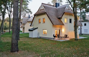 Une maison avec un toit à forte pente, un patio couvert avec des meubles d’extérieur et une pelouse bien entretenue.