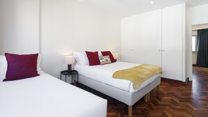 Ein Hotelzimmer mit zwei Betten, einem Kleiderschrank und einem Nachttisch.