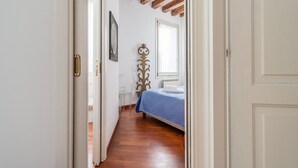 A narrow hallway leading to a bedroom with a bed, a window, and a radiator. - 7 WINDOWS ON VENICE APARTMENT (Venezia)