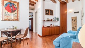 A dining area with a wooden table and chairs, a blue sofa, and a kitchen area with wooden cabinets and a countertop. - 7 WINDOWS ON VENICE APARTMENT (Venezia)