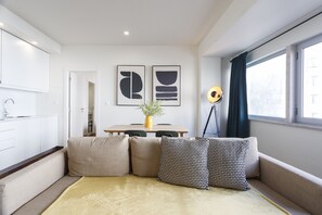 A modern living room with a sofa, a coffee table, and a dining area with a table and chairs.