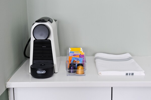 A white desk with a black and white speaker, a clear plastic container with stationery, and a folded white cloth.