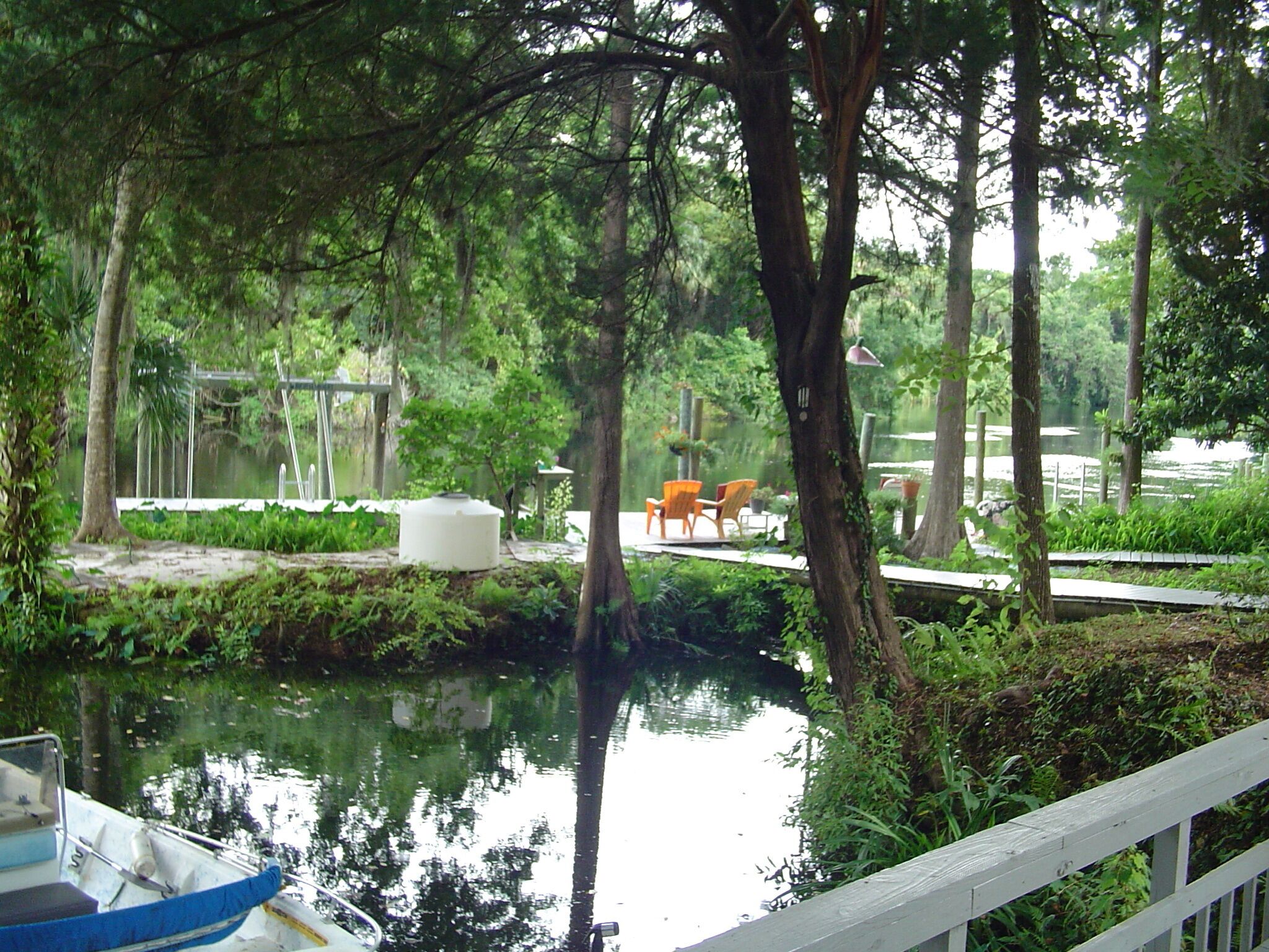 Eine friedliche Flusslandschaft mit einem Steg, Stühlen und einem kleinen Boot.
