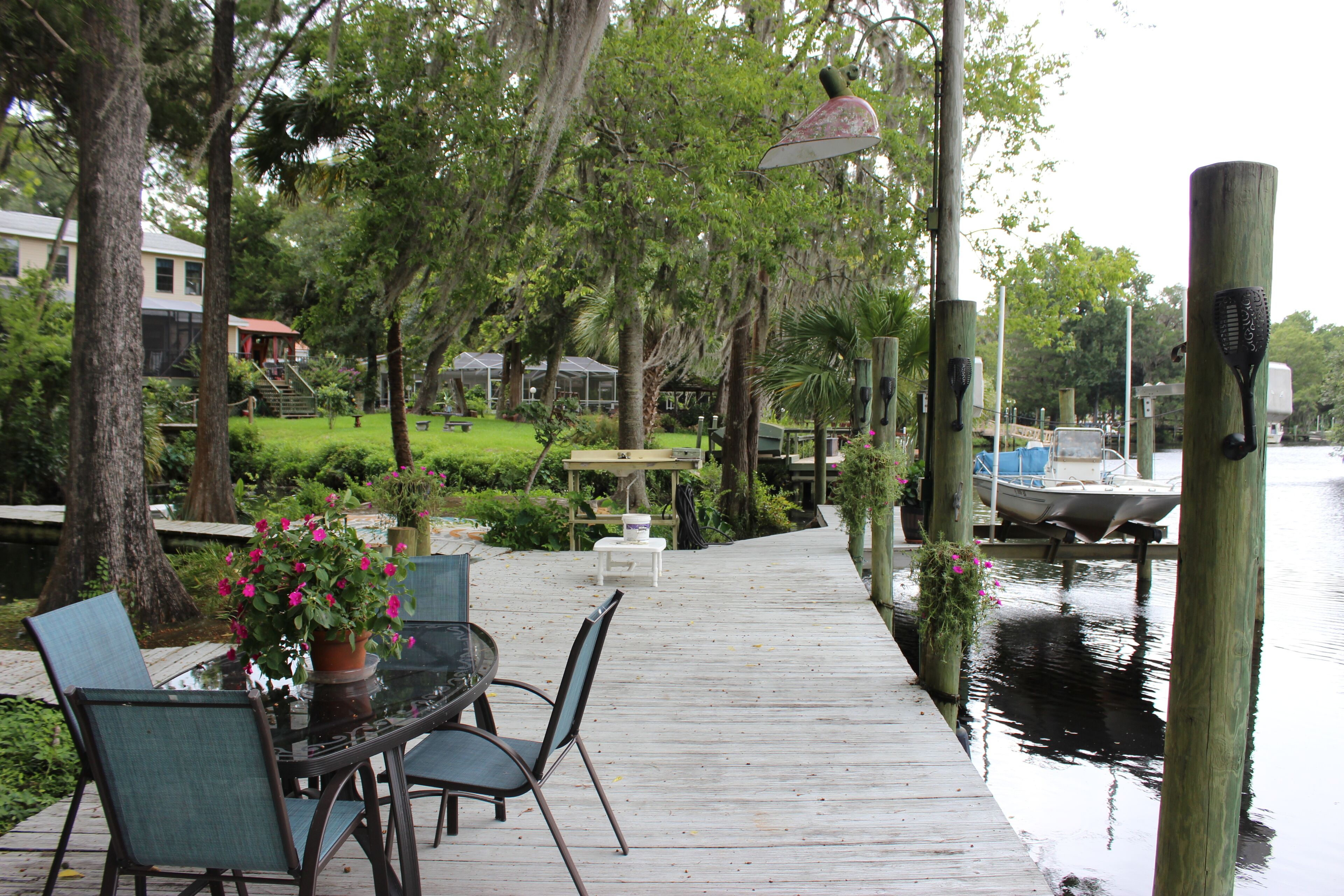 A wooden deck with outdoor seating, overlooking a calm body of water.