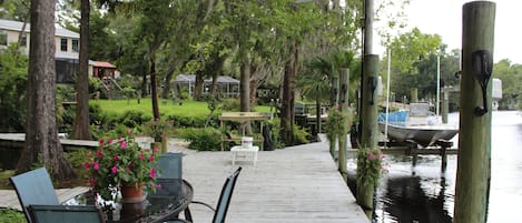 A wooden deck with outdoor seating, overlooking a calm body of water.