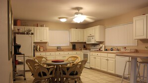 A kitchen with white cabinets, a dining table with chairs, a ceiling fan, and a microwave. - Private, Beautiful & Quiet Guesthouse On The Withlacoochee River (Yankeetown)