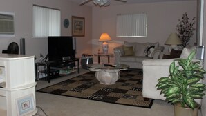 A living room with a ceiling fan, a television, a coffee table, a sofa, and a potted plant. - Private, Beautiful & Quiet Guesthouse On The Withlacoochee River (Yankeetown)