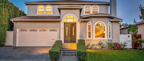 Une maison à deux étages avec un garage, une porte d’entrée dotée d’un panneau de verre et une cheminée.