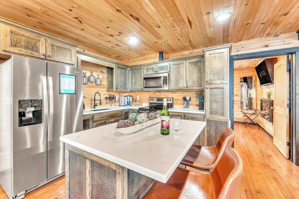 A modern kitchen with wooden cabinets, stainless steel appliances, and a central island with seating.