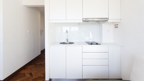 Una cocina moderna con armarios blancos, un lavamanos de acero inoxidable y una campana extractora empotrada.