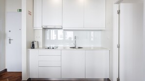 A compact kitchen with white cabinets, a stainless steel sink, and a coffee maker.