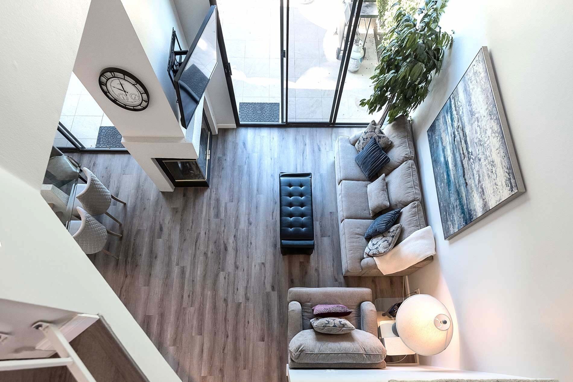 A modern interior with a wooden floor, a sofa set, a clock, and a large window.