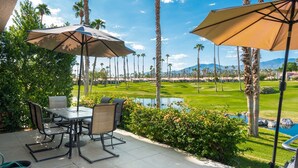 Une terrasse avec des sièges extérieurs, une vue sur un terrain de golf et une piscine.