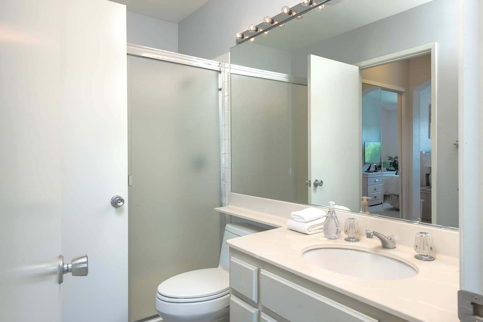 A modern bathroom with a toilet, sink, and mirror.