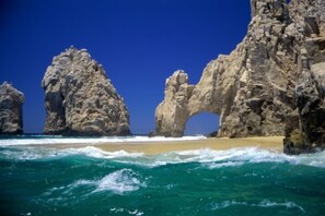 A coastal scene with large rock formations and a clear blue sky. - Luxury Ocean Vu Penthouse Medano Beach -Private rooftop w/spa  (Cabo San Lucas)