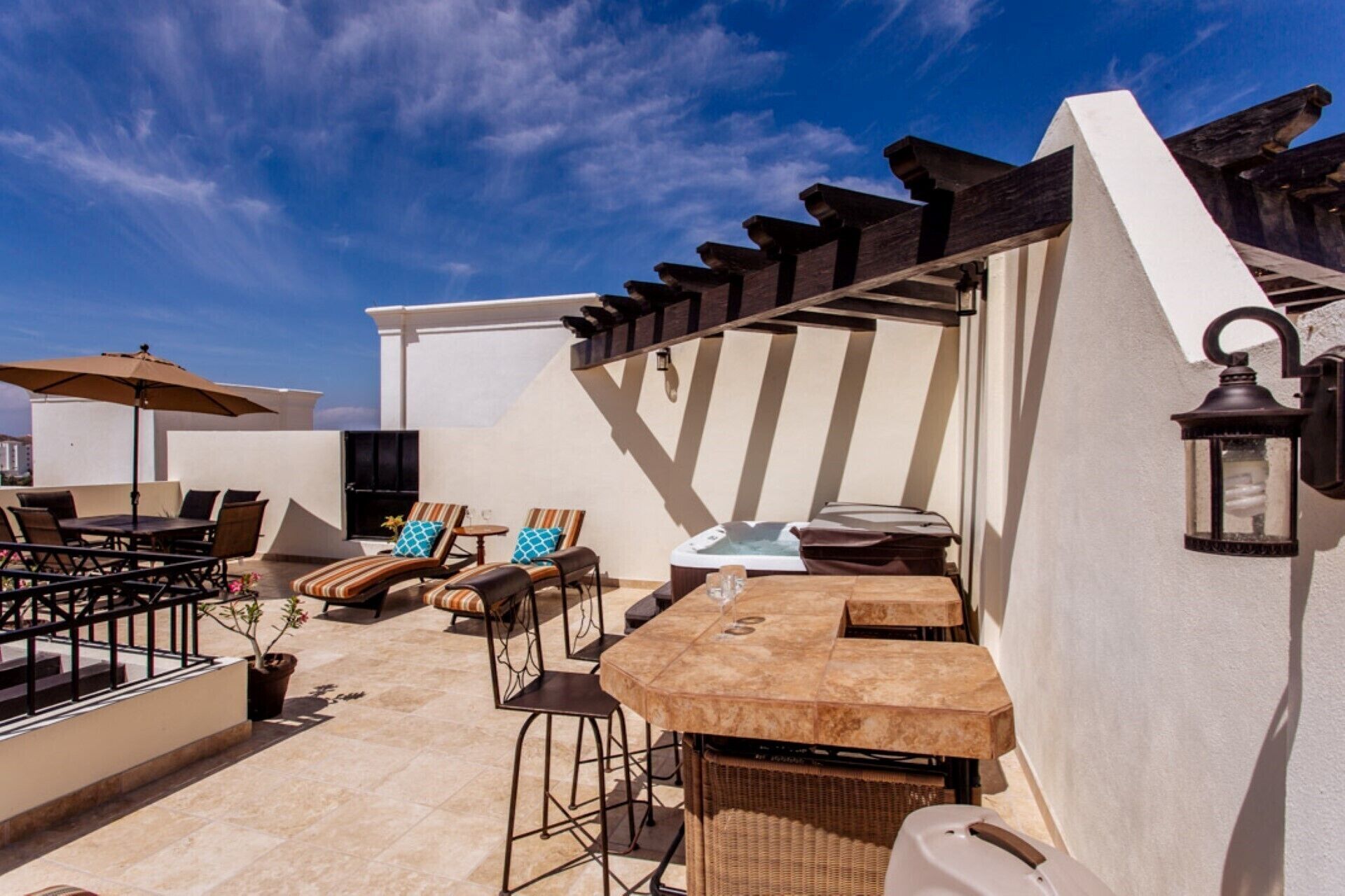 Un patio al aire libre con zona de bar, sillones de descanso y un jacuzzi.