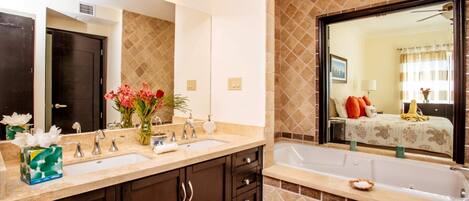 A bathroom with a double sink vanity, a large mirror, and a bathtub.